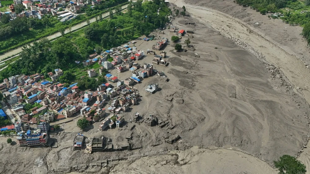 Damaged houses stand precariously near the swollen, debris-choked banks of the Trishuli River after flash floods in Nepal