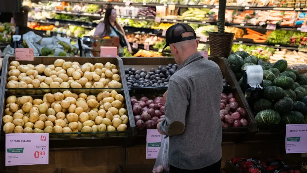 A customer stands in front of fresh produce inside a grocery store.